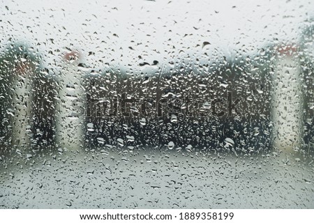 Raindrops falling on a window creating a pictorial effect on the image