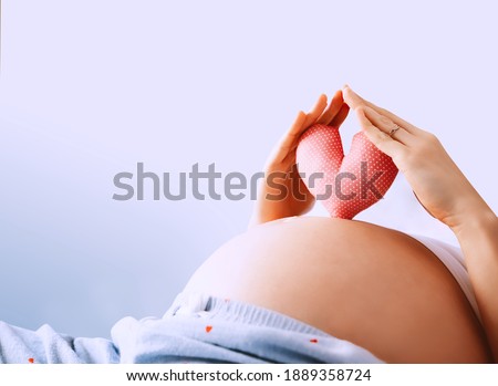 Pregnant woman holds in palms symbol in heart shape. Loving mom waiting of a baby. Concept of maternity, parenting, prepare and expect. Happy expectant mother during pregnancy. Royalty-Free Stock Photo #1889358724