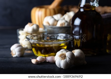 Ripe and raw garlic and garlic oil in glass of bottle on dark wooden background. Garlics and olive oil.  Royalty-Free Stock Photo #1889369692