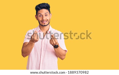 Handsome latin american young man wearing casual summer shirt doing money gesture with hands, asking for salary payment, millionaire business 