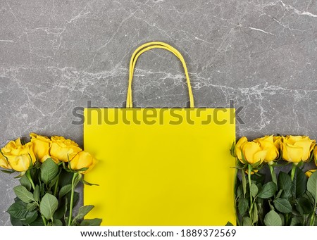 Yellow roses, yellow paper bag on gray background. Gift,holiday,Dating.Valentines day,Mothers day,Womens day flat lay. Spring, seasonal sale