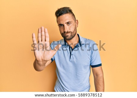 Handsome man with beard wearing casual clothes doing stop sing with palm of the hand. warning expression with negative and serious gesture on the face. 