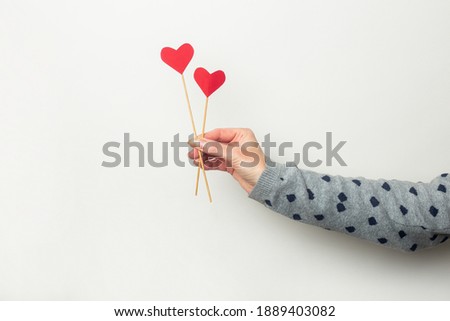 Female hand holds hearts on sticks on a light background. Valentine's day, birthday. Banner.