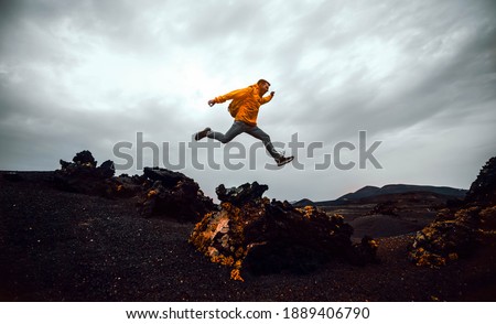 Hiker man jumping over the mountain. Freedom, risk, success and  Royalty-Free Stock Photo #1889406790
