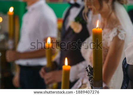 the groom holds a candle in his hands during a wedding in the Orthodox Church.candles in the hands. wedding in the orthodox church. candle fire. bride and groom in a church. wedding customs.