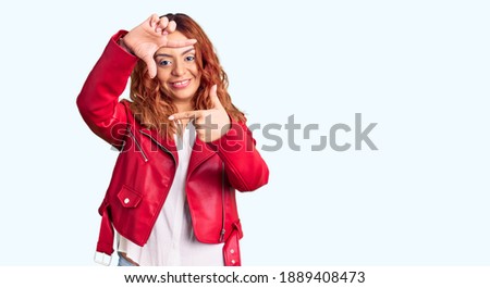 Young latin woman wearing red leather jacket smiling making frame with hands and fingers with happy face. creativity and photography concept. 