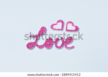 Love word in bright purple with hearts on light blue background. Valentine day concept