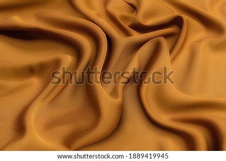 Abstract texture of natural beige or brown color fabric as concept background. Fabric texture of natural cotton or linen, silk or satin, wool or jersey textile material. Luxurious dark background. Royalty-Free Stock Photo #1889419945