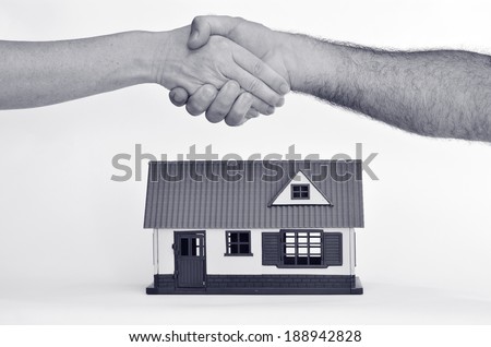 Man and a woman shaking hands over a toy house on white background.Concept photo of real estate business, home  Insurance, house rental, buying, renting, mortgage, selling, finance. Copy space