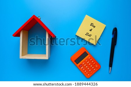 A picture of house miniature with buy and sell on notepad, calculator and pen for real estate ownership concept.
