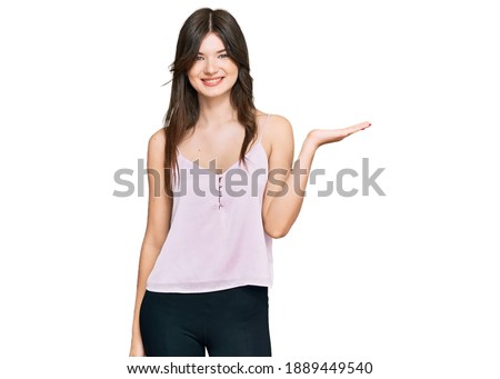 Young beautiful caucasian girl wearing casual clothes smiling cheerful presenting and pointing with palm of hand looking at the camera. 