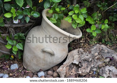 large ceramic decorative jug in the garden, green leaves