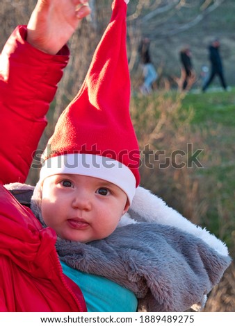 A photo of a beautiful baby girl wearing a red Christmas on a sling with her mother 