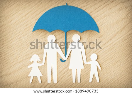 Paper family silhouette with umbrella on wooden background - Concept of family protection