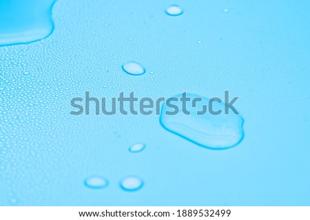 Water drops on light blue background, closeup view.