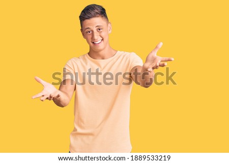 Young handsome man wearing casual clothes smiling cheerful offering hands giving assistance and acceptance. 