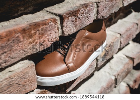 Brown sneakers or shoes with white sole, close up. Bricks background