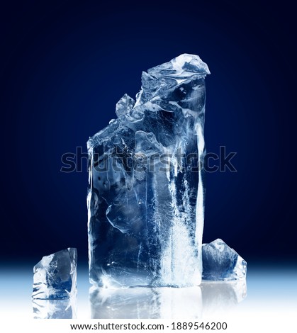 Vertical rectangular block of ice with a broken-off top isolated on a dark blue background with clipping path. Royalty-Free Stock Photo #1889546200