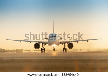 Sunset view of airplane on airport runway under dramatic sky Royalty-Free Stock Photo #1889546404