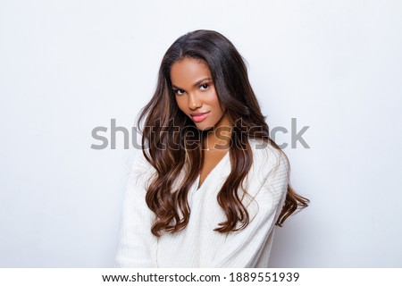 Happy Black Girl Smile in White Sweater with long curly hair. Relaxed and Carefree. Portrait of beautiful black woman in white sweater with long curly hair                  Royalty-Free Stock Photo #1889551939