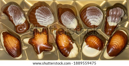 Great design and luxurious taste of delicious chocolates. Wonderful way to magically lift your spirits. Appetizing and delicious chocolate candies on a golden background. Stock photo. 