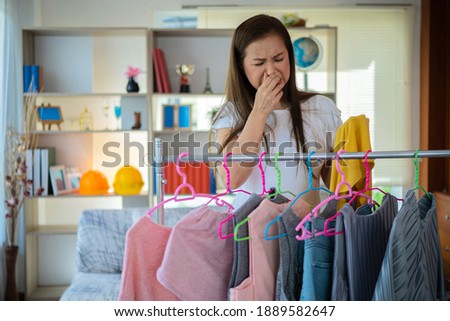 Portrait beautiful housewife. Attractive beautiful asia woman is smelling stinky, musty from her husband shirt. Asian woman will bring shirts for washing at laundry room. She use fingers close nose Royalty-Free Stock Photo #1889582647