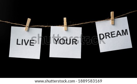 Live your Dreams on white stickers on black background. Motivational phrase. Minimalism and simplicity concept.