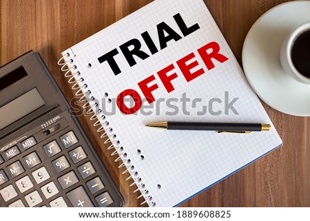 TRIAL OFFER written in a white notepad near a calculator and a cup of coffee on a dark wooden background