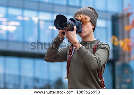 Young woman photographer, Journalist takes pictures on the street, on the street of the city woman holds a camera in her hands.
