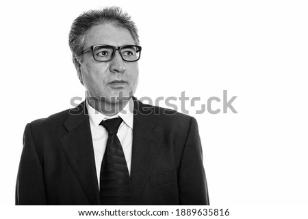Studio shot of senior Persian businessman wearing eyeglasses while thinking