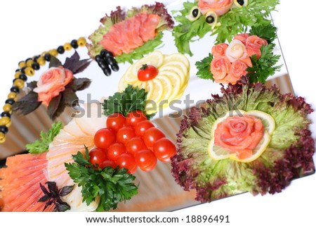 Fish served with vegetables, lemon and herbs on the mirror over white background