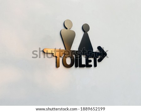 Restroom sign modern black color on white wall with sunlight outdoor. Label toilet symbol for men and women, direction sign and navigation pointer WC restroom indoor or outdoor with nature lighting