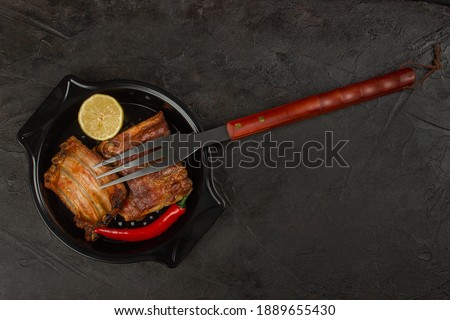 Baked pork ribs with lemon and hot pepper and a barbecue fork