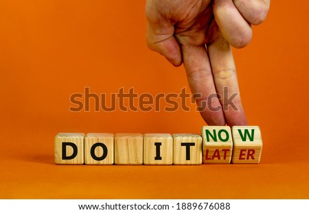 Do it now symbol. Businessman hand turns cubes and changes words 'do it later' to 'do it now'. Beautiful orange background. Business and do it now concept. Copy space.