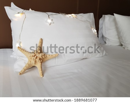 Starfish on a white pillow. Light bulbs decorate the bed. Summer mood in the hotel.