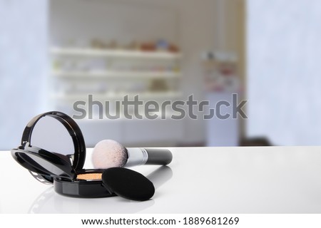 Closeup of decorative composition of powder, brush cosmetic with mirror on table over blurred stylist room. Template for your display product montage. Space. Royalty-Free Stock Photo #1889681269