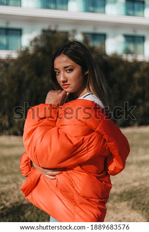 young woman in orange coat posing for fashion