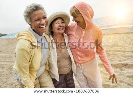 Portrait of happy multi ethnic middle aged female friends enjoying vacation at beach Royalty-Free Stock Photo #1889687836