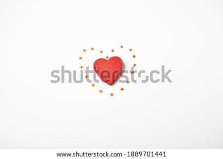 Red wooden heart and little golden stars on the light (white) background. Valentine's Day concept. Flat lay, top view.