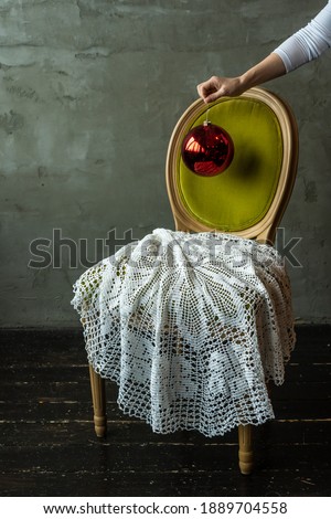 hand holds red christmas ball over chair