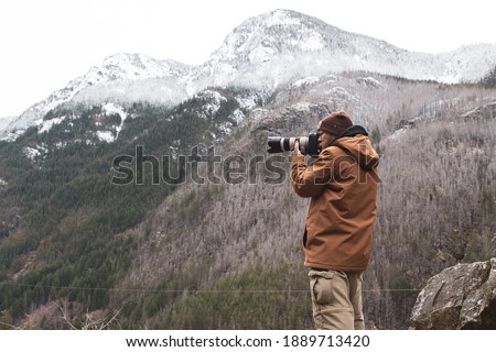 A man holds a camera and takes photos of scenery in nature