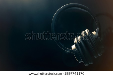 Black professional headphones on a black background. Musical production. Sound studio equipment. Sound engineer working tool. Closed-back Headphones for music lovers. Black on black. Contours  Royalty-Free Stock Photo #1889741170