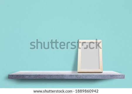 Empty photo frame wood on concrete shelves with cement pastel background.