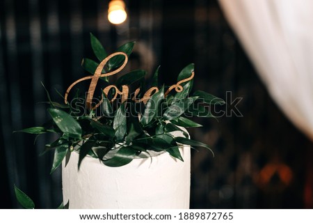 wedding cake white three floors with the inscription LOVE white mastic cream decorated with herbs on a wooden stand