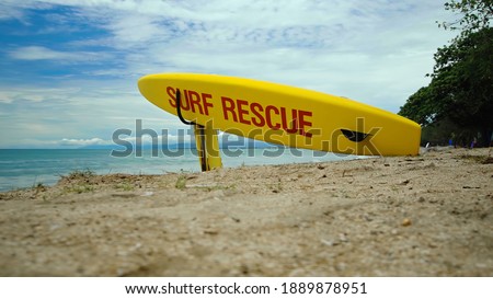 Yellow surfboard on beach with red text surf rescue emergency on a beach on a Bali island
