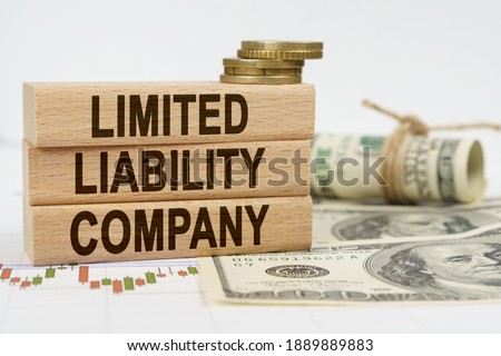 Business and finance concept. On the table are dollars, financial charts and wooden plates on which it is written - LIMITED LIABILITY COMPANY Royalty-Free Stock Photo #1889889883
