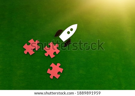 The rocket is white and black, the puzzles are red on a green background. Striving for professional growth. The achievement of the goal.