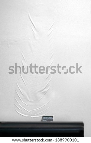 Textured large paint bubble or blister on white painted wall in staircase. Paint rippling from being soaked with water. Concept for signs of water leaks or water mitigation and restoration.