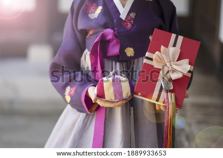 Woman in Korean traditional dress holding lucky bag with gift box
 Royalty-Free Stock Photo #1889933653