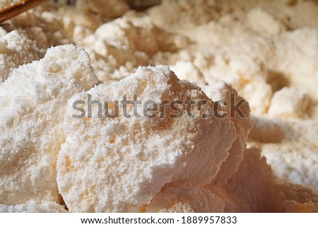Close up and focus to white salt rock pond with white smoke against wooden background located in small Thai village, ฟncient Thai agriculture, Sinthao Salt Pit, Nan district, Thailand
             